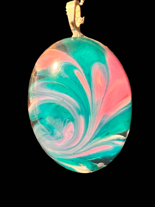 Oval shaped pendant with teal, pink and white swirl beginning at the bottom and swirling upward in a feathery formation. 